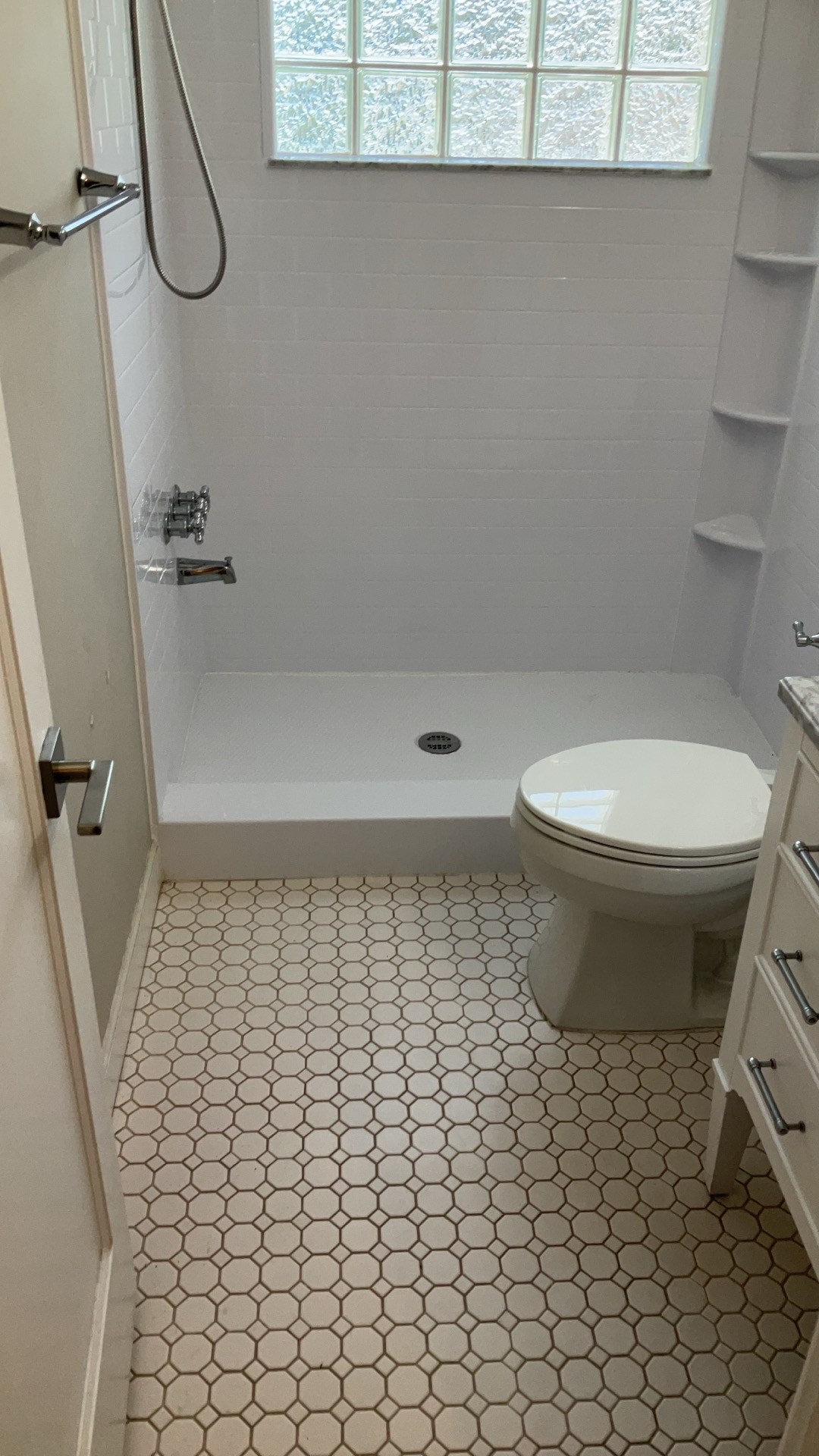 Bathroom shown from the doorway — full view of the walk-in shower, vanity, and octagon-tile floor (real Karhan project, College Park)